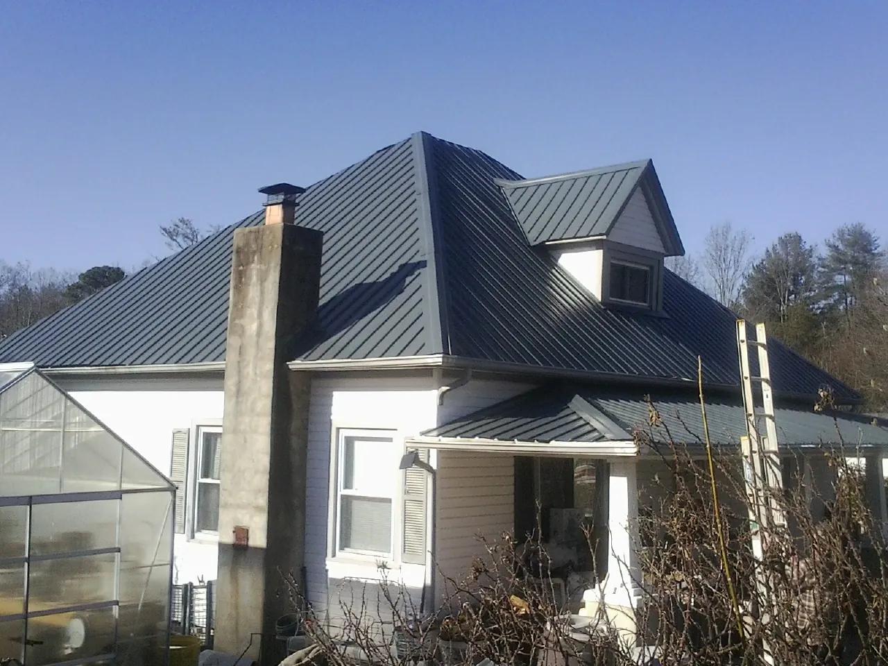 Dark blue standing seam metal roof on a white farmhouse with dormer — Slate & Tile Roof Repair by Roofing Brothers in Nisswa