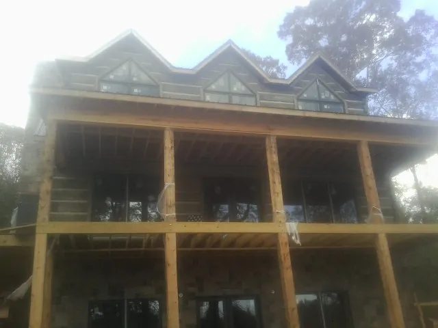 Dormers and porch framing on a large log home under construction — Roof Coating work by our crew in Nisswa