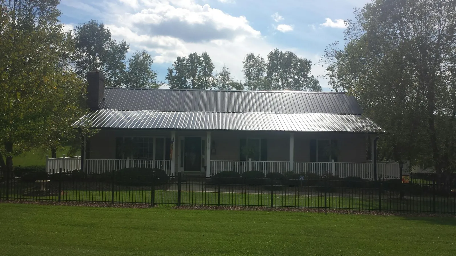 Gray metal roof on a brick ranch with a full width front porch — Gutter Guard Installation work by our crew in Nisswa