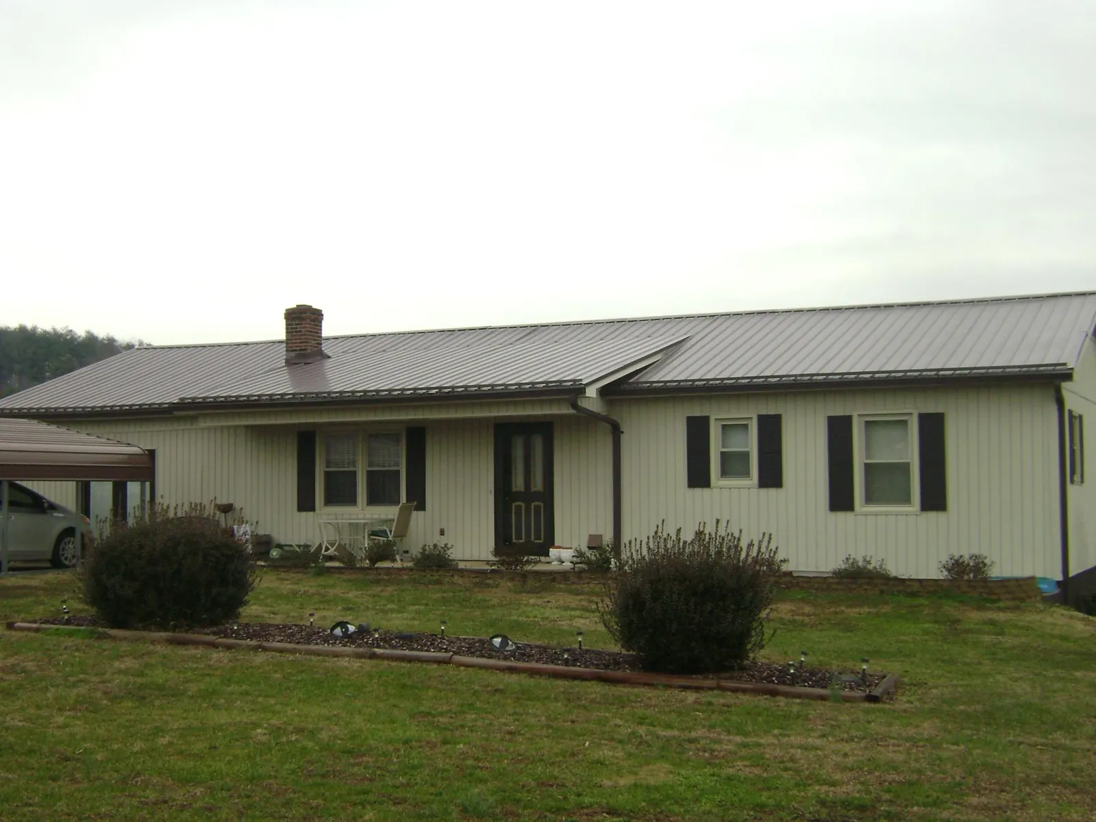 Brown metal roof on a cream sided ranch home with a brick chimney in Nisswa