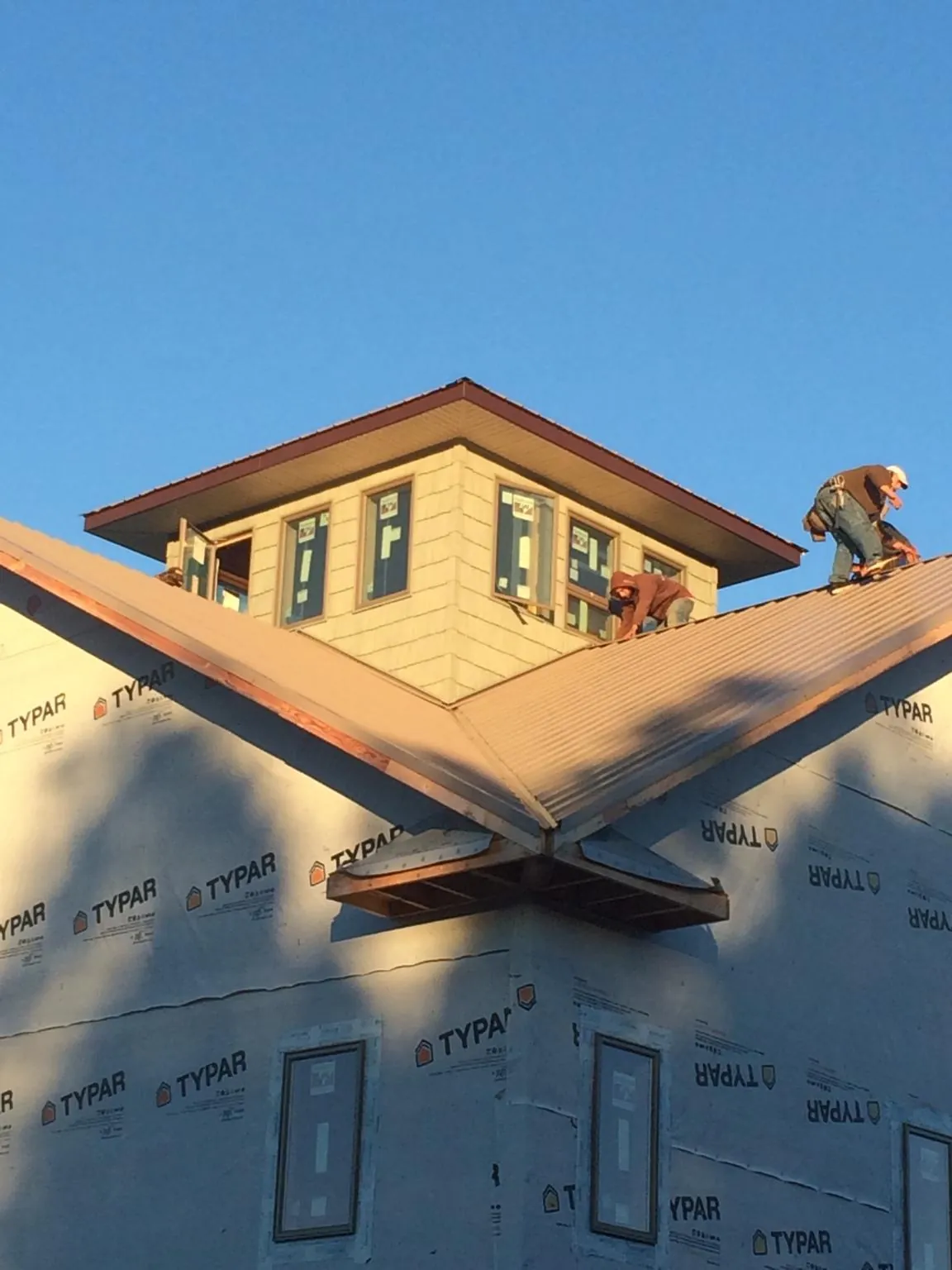 Roofers working around a rooftop cupola on a new metal roof at sunset — Roof Waterproofing in Nisswa by Roofing Brothers
